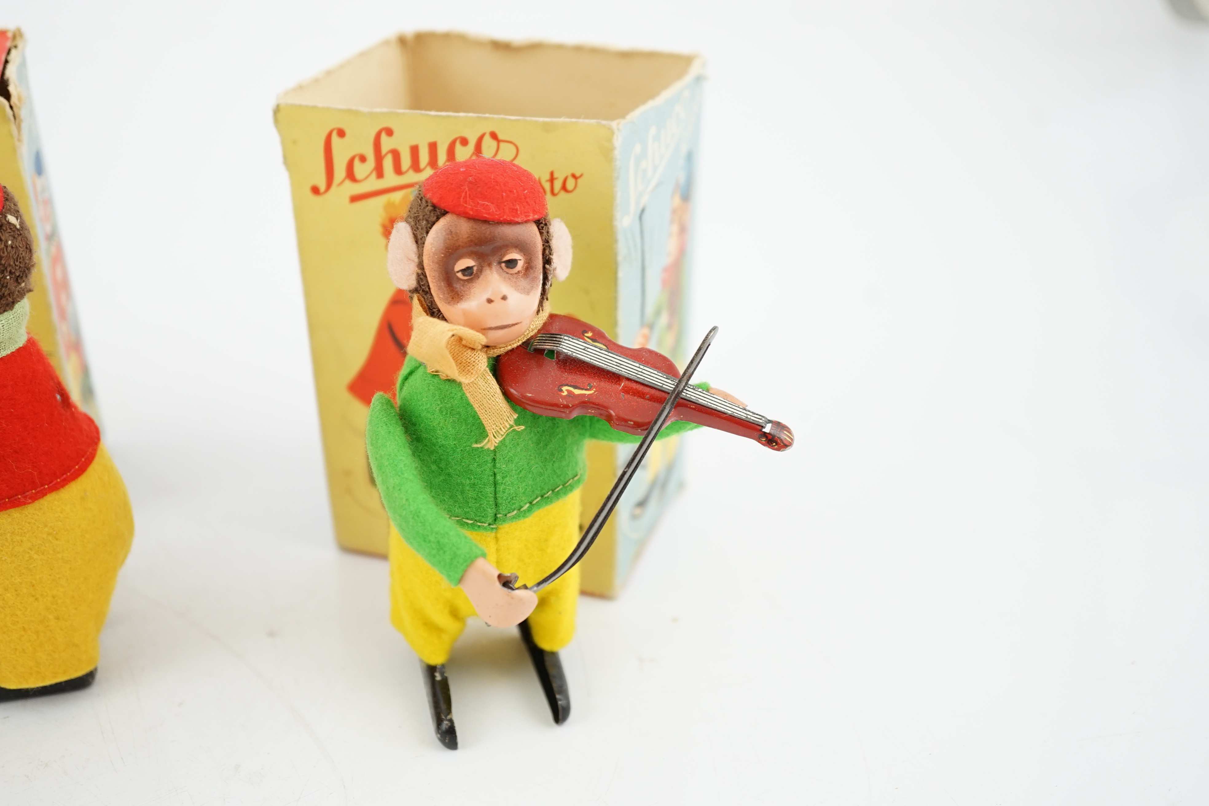 Three Schuco tinplate and felt clockwork monkeys; Hopsa, Solisto and Sousto, all contained within the remains of their boxes, 11cm high